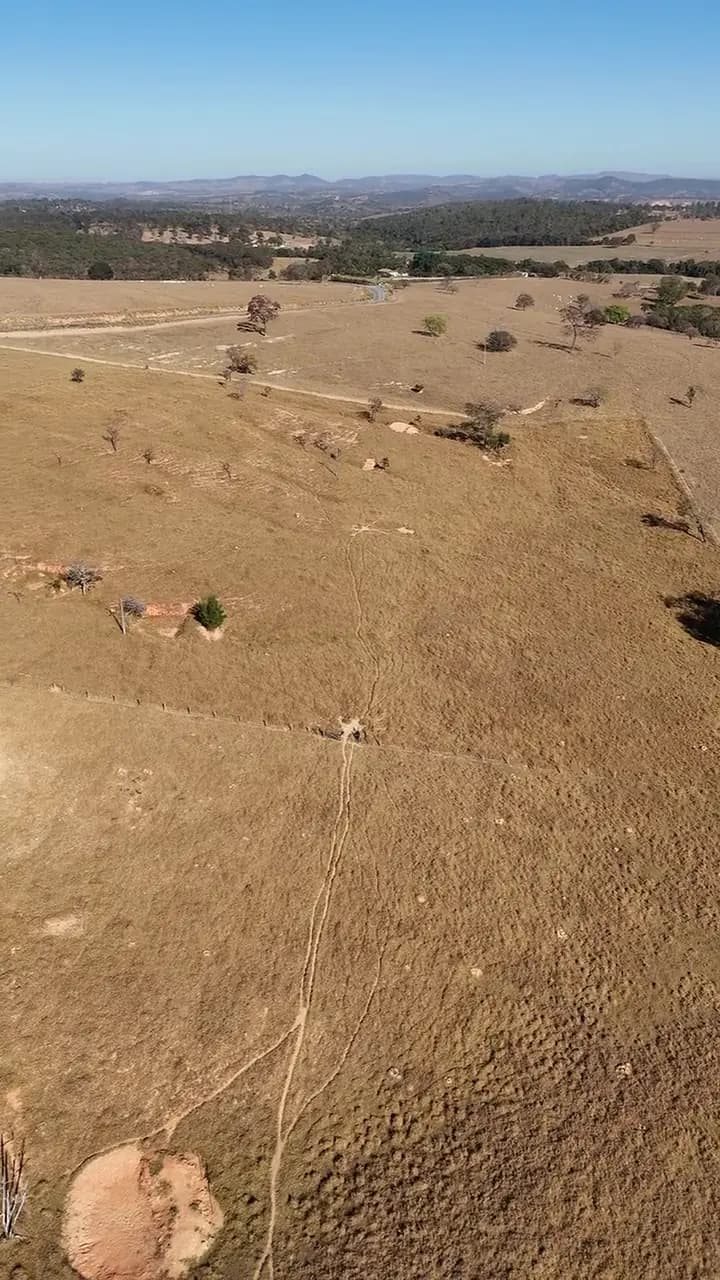 Vista aérea do campo aberto do empreendimento, com a linha de morros no horizonte